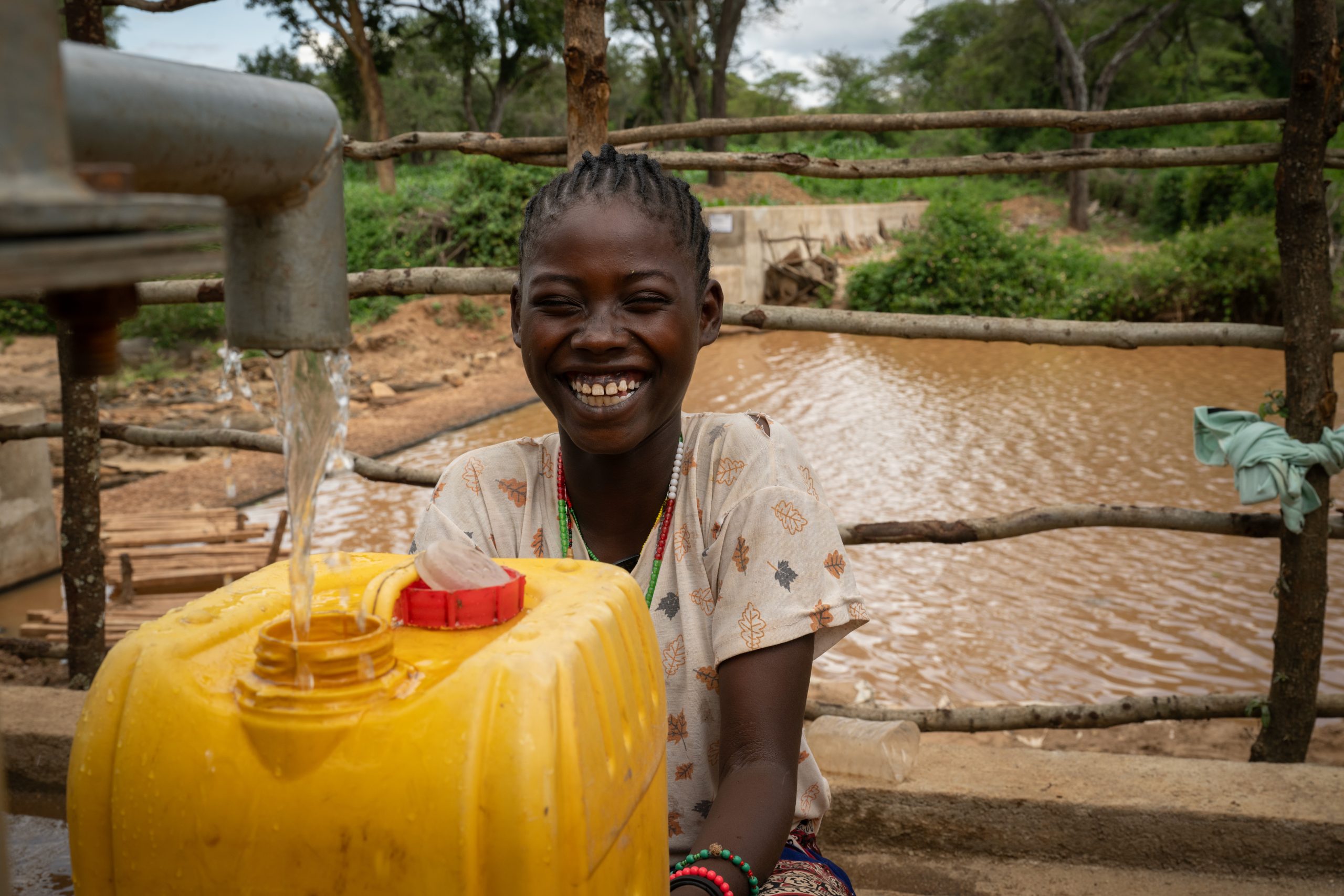 Tsion (12) sitter ved vannposten som gir landsbyen tilgang til rent og trygt drikkevann.